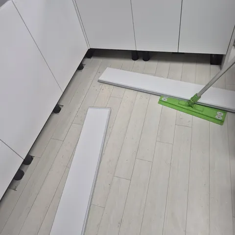 분리된 하부장 걸레받이가 바닥에 놓인 상태에서 밀대로 바닥을 닦는 모습