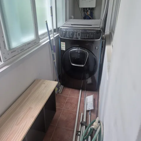 세탁기와 보일러, 수납장이 있는 길쭉한 베란다 전경
