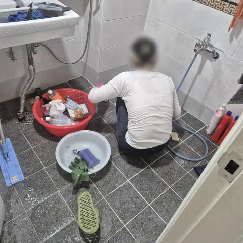 물을 뿌린 욕실 바닥과 대야, 세정 용품이 놓인 작업 모습