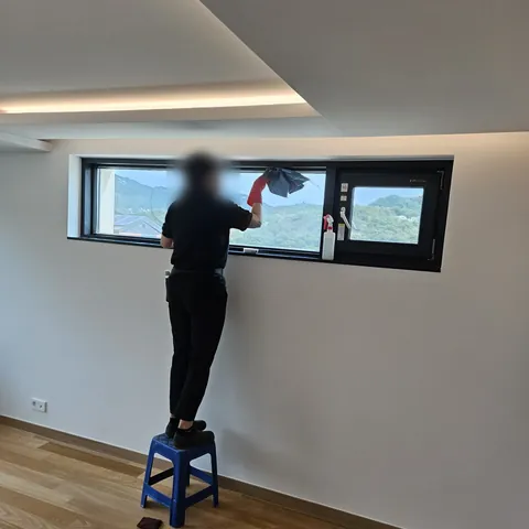 발판 위에서 가로로 긴 창을 닦는 작업 모습