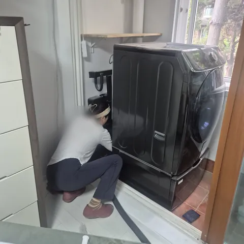세탁기 옆 바닥을 쪼그려 앉아 청소하는 작업 모습