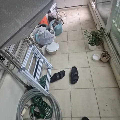 타일 바닥에 호스와 사다리, 화분이 놓인 베란다